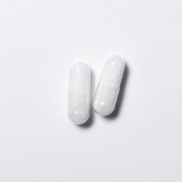 White vegan neotes L-carnitine capsules in close-up on a light background