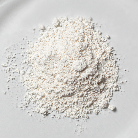 Fine white resveratrol powder in close-up on a light, minimalist background