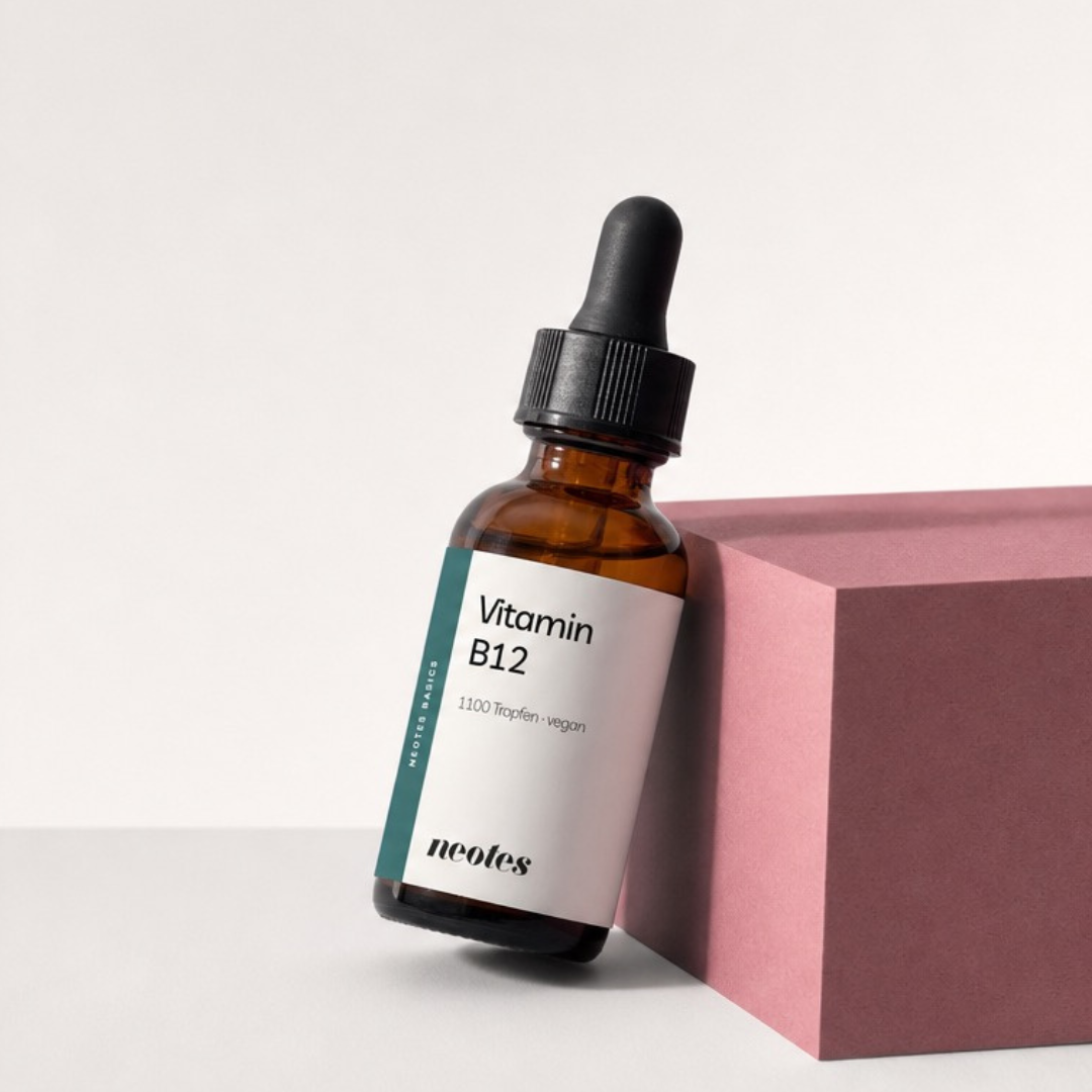 Vitamin B12 Tropfen von neotes als Packshot mit Braunglasflasche und rosafarbenem Block